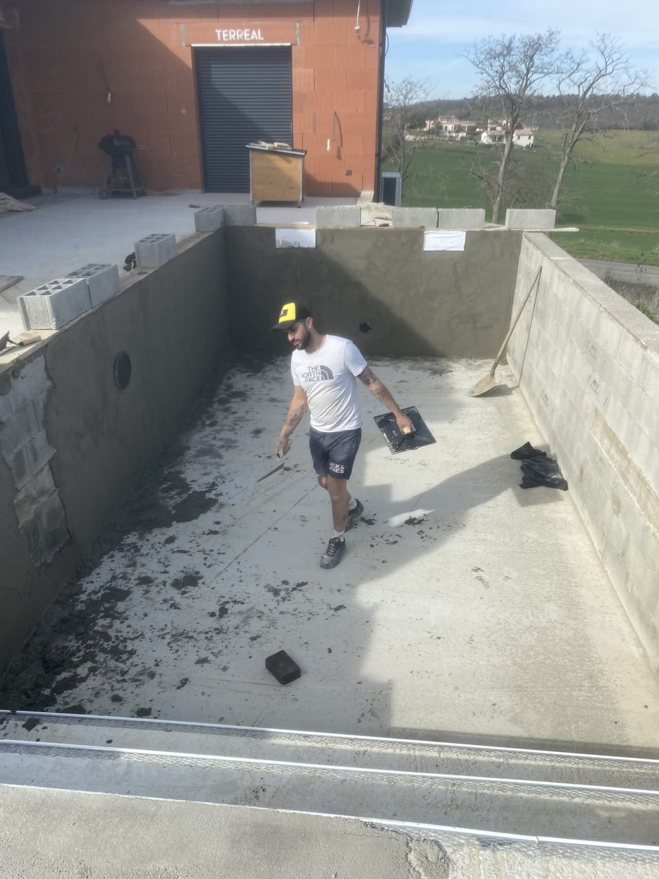 Maçon de l'Entreprise Felicioni en train d'enduire l'intérieur d'un bassin de piscine en béton à Pujaudran