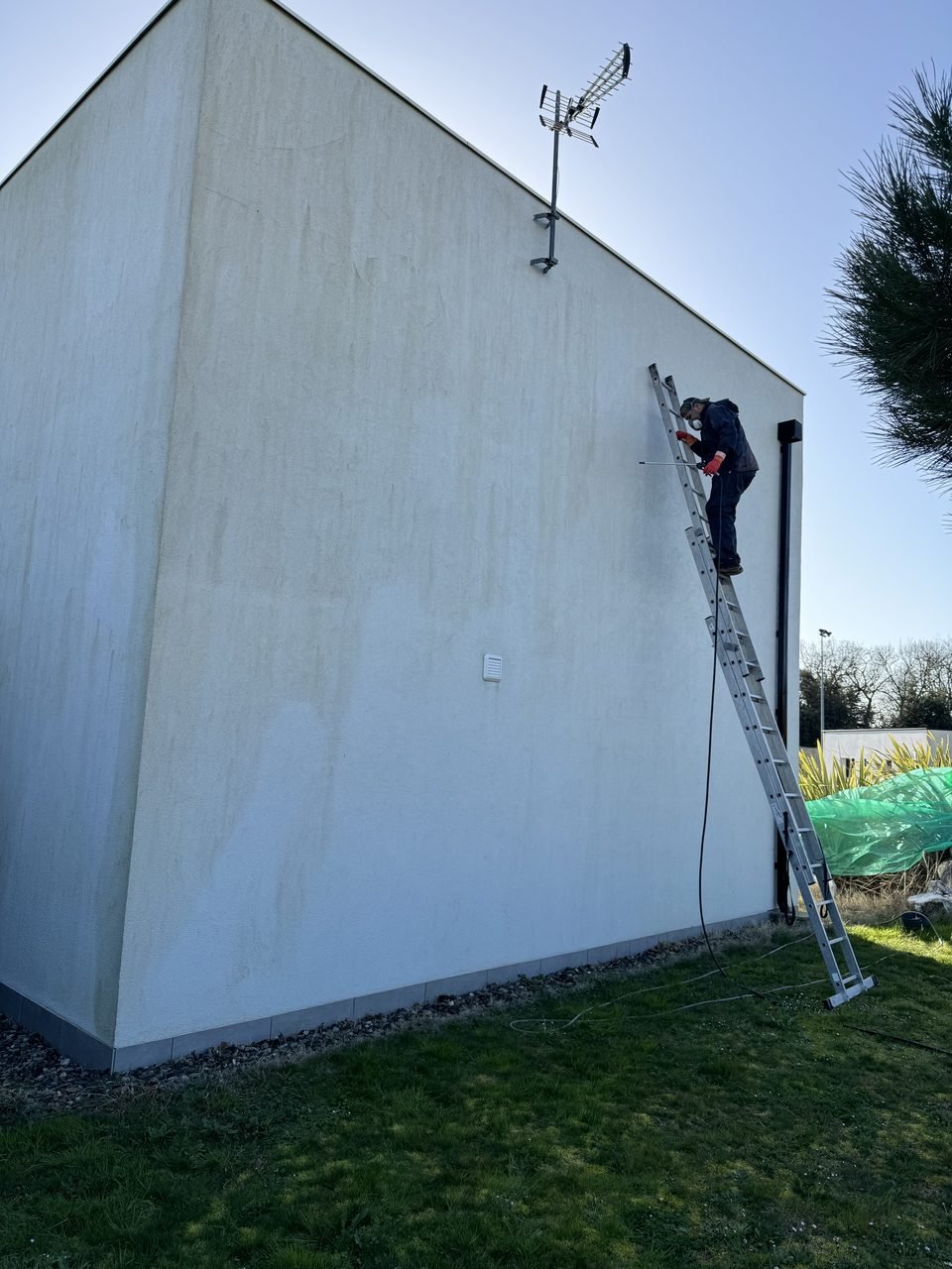 Nettoyage d’une façade crépi avec masque de protection et lance basse pression à Préserville
